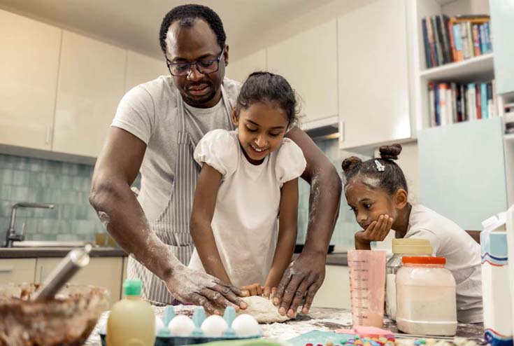 Man cooking in kitchen with two girls